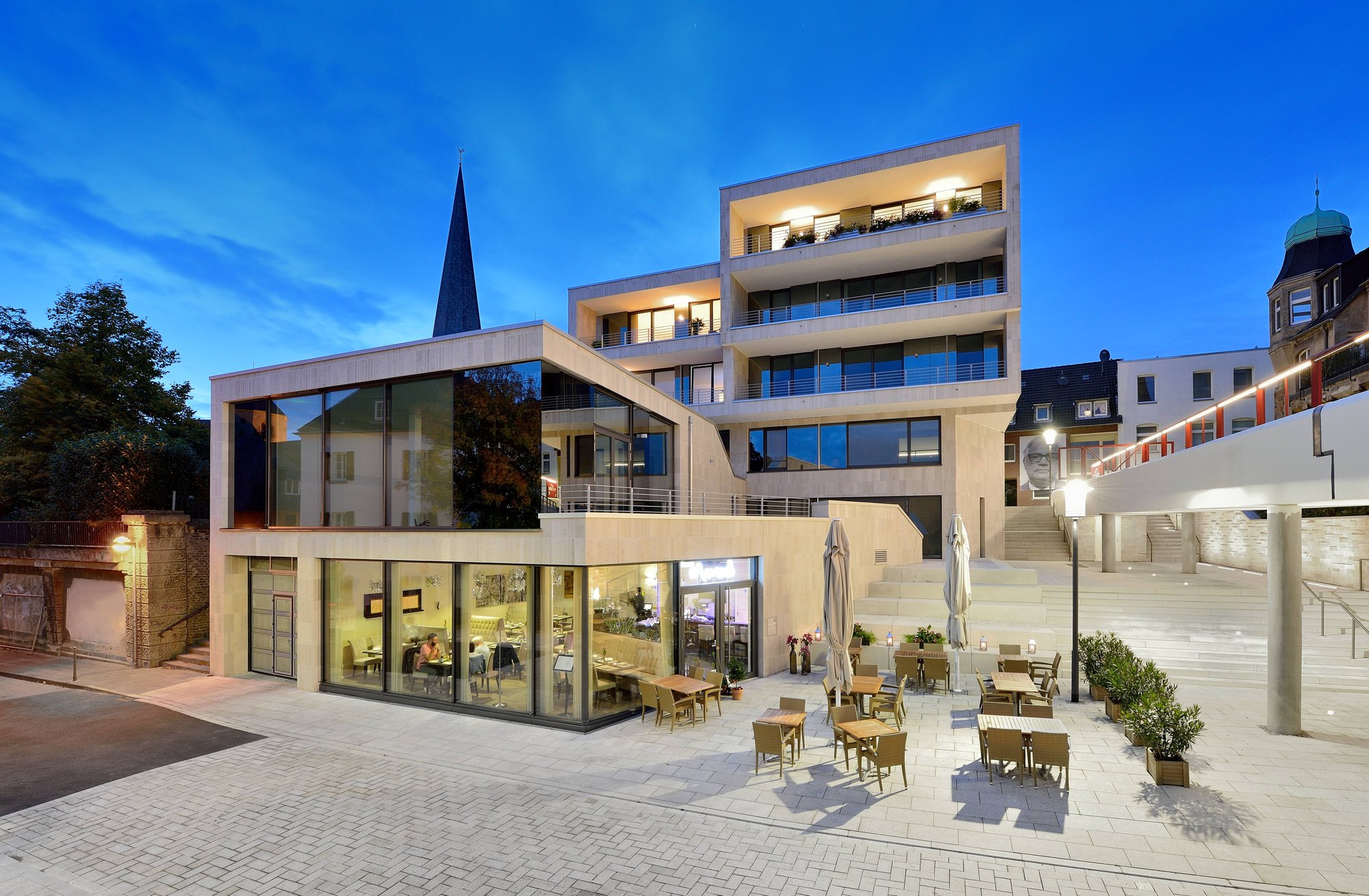 Wohn- und Geschäftshaus mit Außengastronomie zur blauen Stunde