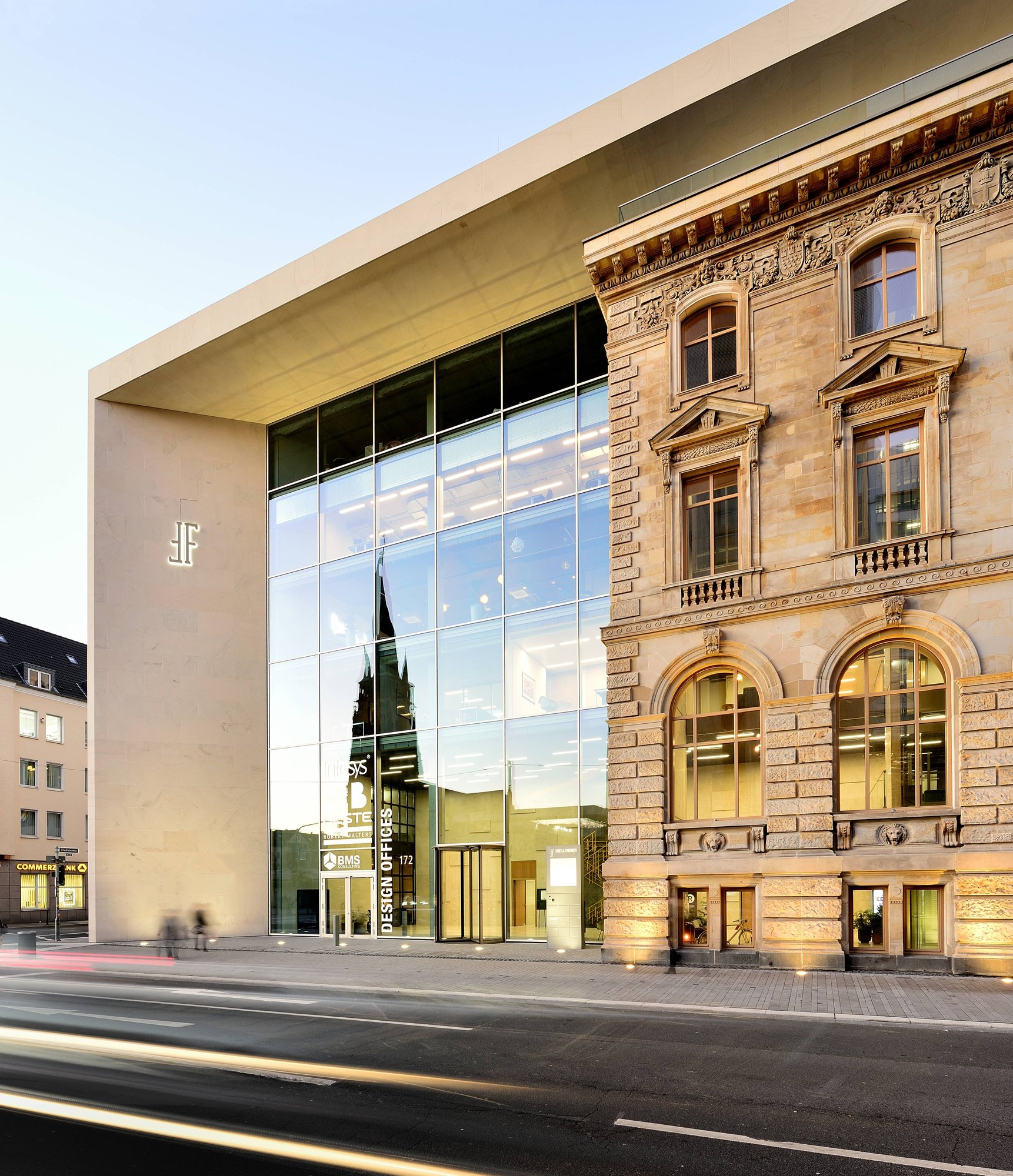 Gläserner Neubau neben historischer Sandsteinfassade